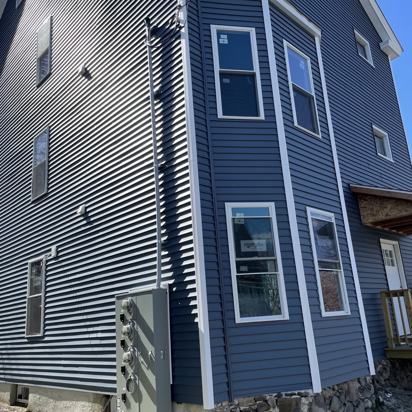 The same bay corner in April, fully sided in blue with white trim