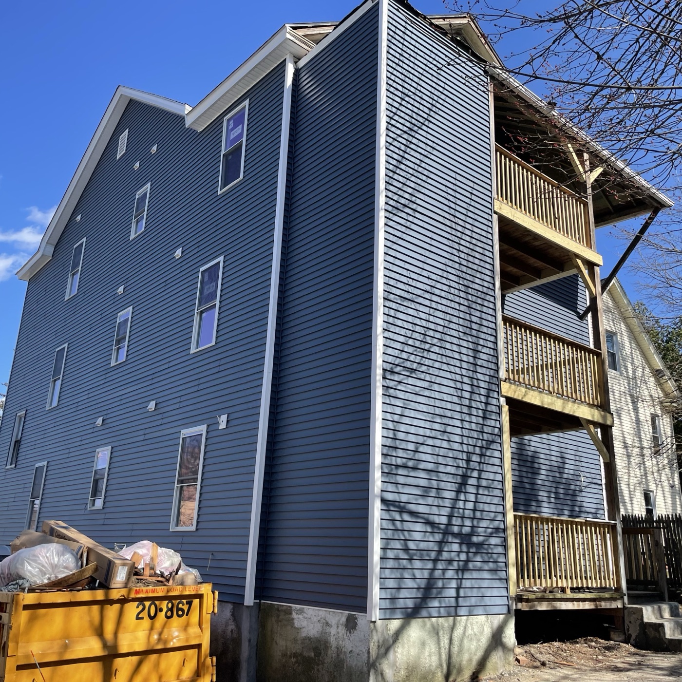 The same gable end in April, finished in blue siding with the porches rebuilt